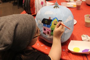 Student carefully adds the finishing touches to her painted pumpkin. Photo by Hannah Haggerty. 
